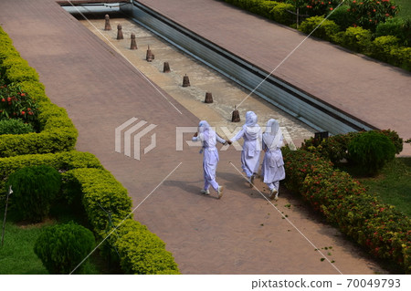 A Muslim schoolgirl walking along the sidewalk of the unfinished castle ruins of Lalbagh Fort Gardens in Dhaka, Bangladesh 70049793