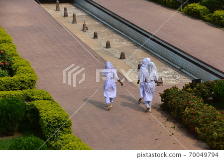 A Muslim schoolgirl walking along the sidewalk of the unfinished castle ruins of Lalbagh Fort Gardens in Dhaka, Bangladesh A Muslim schoolgirl walking along the sidewalk of the unfinished castle ruins of Lalbagh Fort Gardens in Dhaka, Bangladesh 70049794