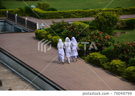 A Muslim schoolgirl walking along the sidewalk of the unfinished castle ruins of Lalbagh Fort Gardens in Dhaka, Bangladesh A Muslim schoolgirl walking along the sidewalk of the unfinished castle ruins of Lalbagh Fort Gardens in Dhaka, Bangladesh 70049799