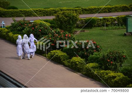 A Muslim schoolgirl walking along the sidewalk of the unfinished castle ruins of Lalbagh Fort Gardens in Dhaka, Bangladesh A Muslim schoolgirl walking along the sidewalk of the unfinished castle ruins of Lalbagh Fort Gardens in Dhaka, Bangladesh 70049800
