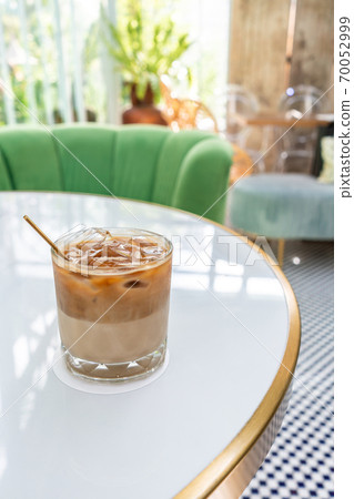 Ice coffee in a tall glass with milk poured over 70052999