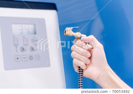Close up man hand holding mechanic inflating tire and checking air pressure with gauge pressure in service station Close up man hand holding mechanic inflating tire and checking air pressure with gauge pressure in service station 70053892