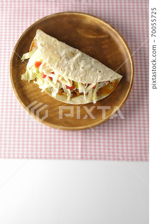 Tacos with cheese, cherry tomatoes, minced meat, etc. placed on a round wooden plate (overhead view) 70055725