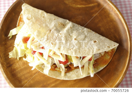 Tacos with cheese, cherry tomatoes, minced meat, etc. placed on a round wooden plate (overhead view) 70055726