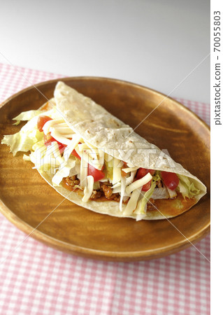 Tacos with cheese, cherry tomatoes and minced meat placed on a round wooden plate Tacos with cheese, cherry tomatoes and minced meat placed on a round wooden plate 70055803