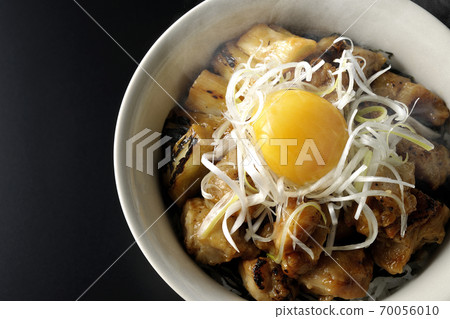 A hot bowl of white-haired green onions and egg yolks on top of a charcoal-grilled yakitori (black background, bird's-eye view) 70056010