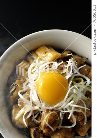 A hot bowl of white-haired green onions and egg yolks on top of a charcoal-grilled yakitori (black background, bird's-eye view) 70056013
