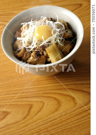 A hot bowl of white-haired green onions and egg yolks on top of a charcoal-grilled yakitori 70056071