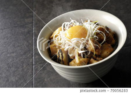A hot bowl of white-haired green onions and egg yolks on top of a charcoal-grilled yakitori 70056283