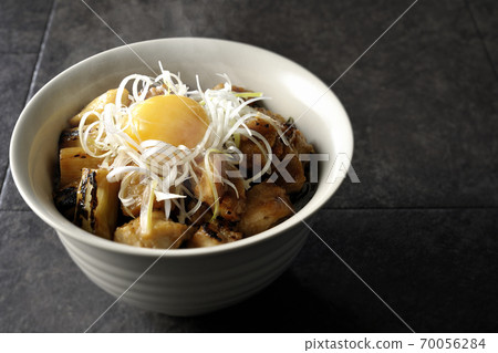 A hot bowl of white-haired green onions and egg yolks on top of a charcoal-grilled yakitori 70056284