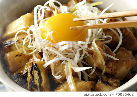 Eat the yolk of a hot yakitori bowl with white onions and egg yolk on top of a charcoal-grilled yakitori with chopsticks. Eat the yolk of a hot yakitori bowl with white onions and egg yolk on top of a charcoal-grilled yakitori with chopsticks. 70056468