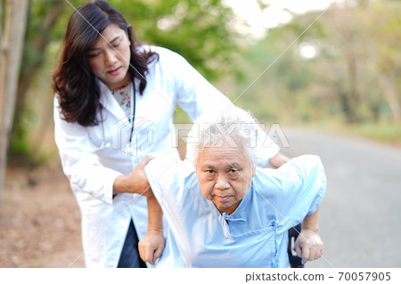 Doctor help and care Asian senior or elderly old lady woman patient sitting on wheelchair at park in nursing hospital ward, healthy strong medical concept 70057905