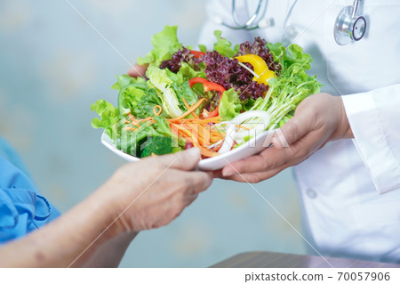 Asian senior or elderly old lady woman patient eating breakfast vegetable healthy food with hope and happy while sitting and hungry on bed in hospital. 70057906