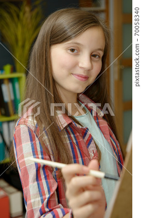 Smiling young teen painting a canvas Smiling young teen painting a canvas 70058340
