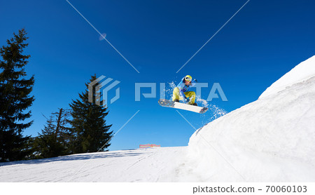 Snowboarder at jump inhigh mountains at sunny day. 70060103