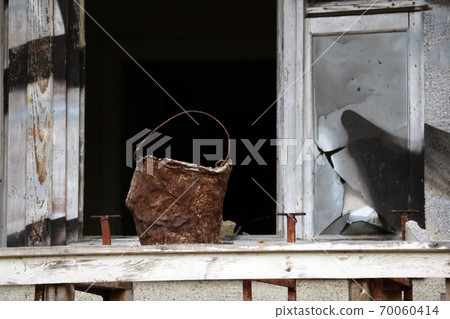 An old rusty bucket stands in the window. Fire extinguishing. An old rusty bucket stands in the window. Fire extinguishing. 70060414