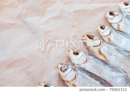 Dried fishes flat lay template banner on craft paper background with empty space for text. Salted roach web cover backdrop. Seafood snack poster, flyer decorative design. Fish frame promotion shop Dried fishes flat lay template banner on craft paper background with empty space for text. Salted roach web cover backdrop. Seafood snack poster, flyer decorative design. Fish frame promotion shop 70062312
