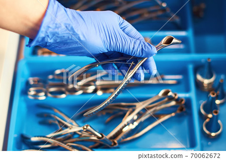 Doctor's hand in disposable nitrile medical gloves holding a nasal speculum for ENT examination 70062672