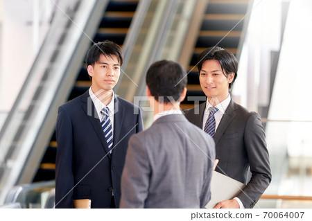 A businessman having a conversation in front of an escalator 70064007