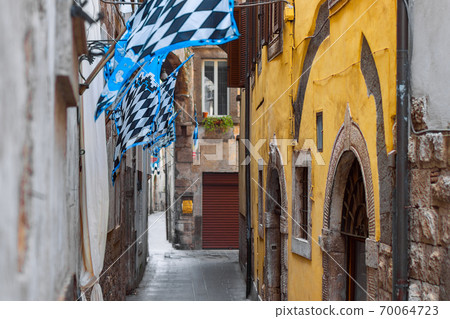 A narrow street of the city of Orte in Umbria decorated with traditional medieval flags 70064723
