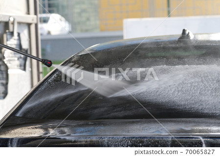 self-washing car service, washes away car shampoo from automobile back window, black car washing, simple work, selective focus 70065827