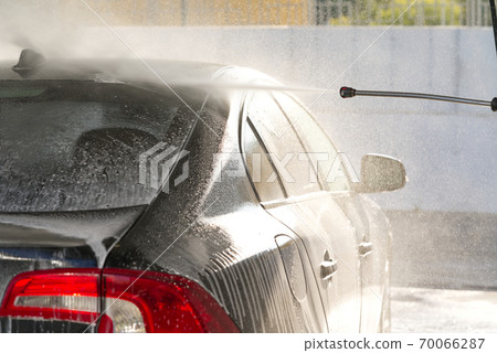 self-washing the car, washes away car shampoo from roof, black car washing, selective focus 70066287