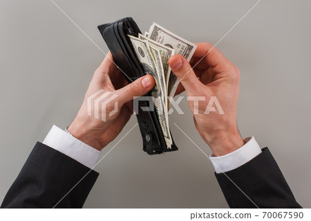 Businessman taking money out of purse. 70067590