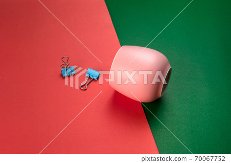 pink ceramic tea cup with blue paper clip on red green background pink ceramic tea cup with blue paper clip on red green background 70067752
