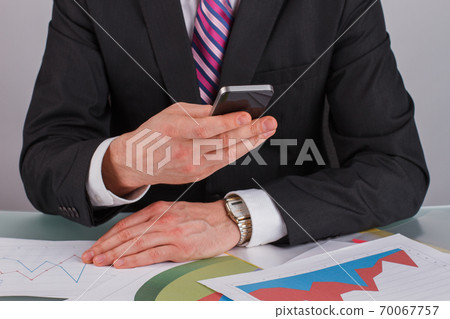 Close up businessman using smartphone sitting at office. Close up businessman using smartphone sitting at office. 70067757