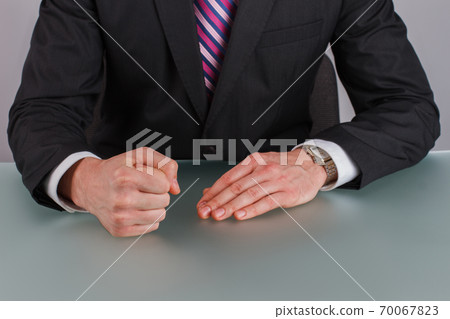 Businessman with clenched fist on desk at office. 70067823