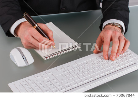 Businessman working at desktop in office. Businessman working at desktop in office. 70067844
