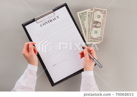 Female hand holding pen ready to put signature on official paper. 70068653