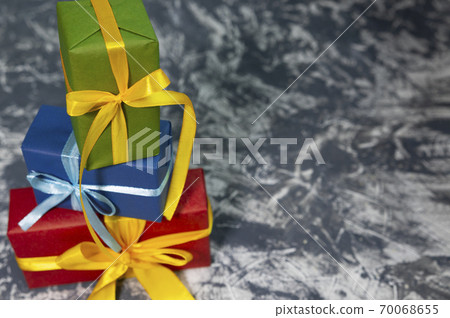 Three stylish multicolored gift boxes with bright ribbons on white and grey background. Space for text. New year concept. 70068655