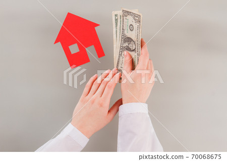 Female hands holding money on table with paper house. Female hands holding money on table with paper house. 70068675