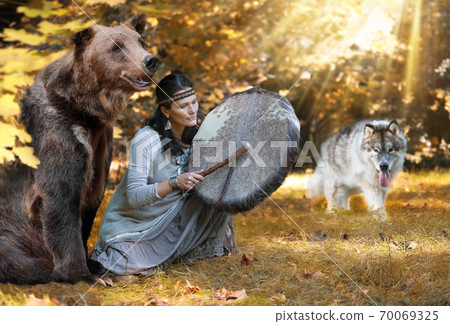 Female shaman plays a tambourine among wild animals 70069325