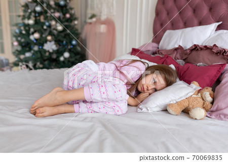 The little girl doesn't want to go to bed on Christmas night. Christmas tale. Magic moments of happy childhood The little girl doesn't want to go to bed on Christmas night. Christmas tale. Magic moments of happy childhood 70069835