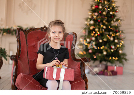 A little girl opens a Christmas present from Santa. Christmas tale. Happy childhood 70069839
