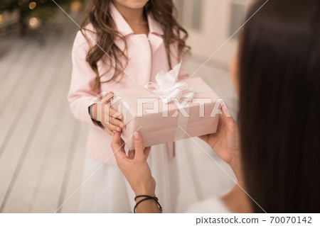 Mom gives her beloved daughter a box with a Christmas present Mom gives her beloved daughter a box with a Christmas present 70070142