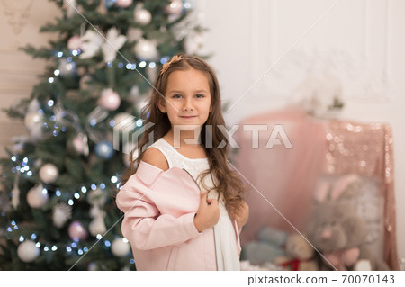 Beautiful little girl posing near the Christmas tree Beautiful little girl posing near the Christmas tree 70070143
