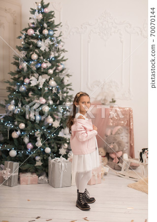 Beautiful little girl posing near the Christmas tree Beautiful little girl posing near the Christmas tree 70070144