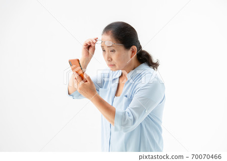 看有老花鏡的資深婦女一個智能手機 70070466