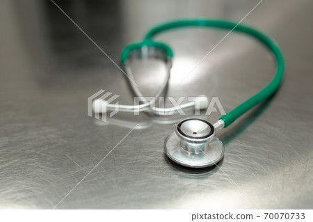 A green stethoscope is lying on a metal table in a clinic. steel background 70070733