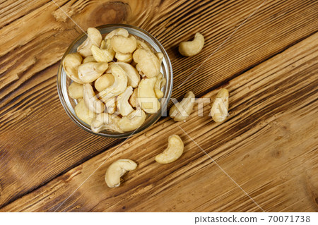 Glass bowl with raw cashew nuts on a wooden table. Top view 70071738