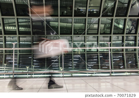 A man walking with luggage in blurred motion at airport hall. A man walking with luggage in blurred motion at airport hall. 70071829