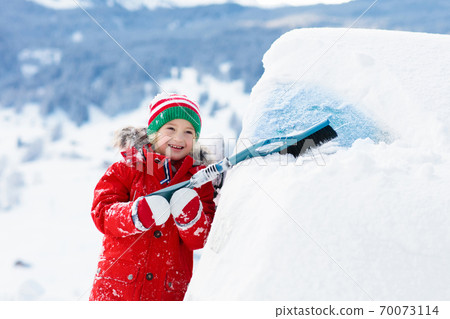 Child brushing off car. Kid with winter snow brush Child brushing off car. Kid with winter snow brush 70073114