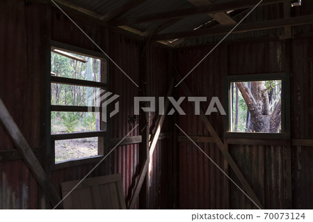 Inside an old building looking out the window at a forest Inside an old building looking out the window at a forest 70073124