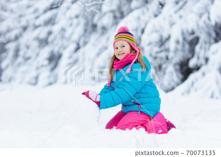 Child making snowman. Kids play in snow in winter Child making snowman. Kids play in snow in winter 70073135