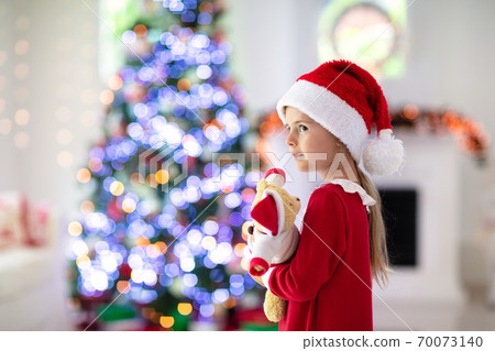 Little girl opening Christmas presents at fire place Little girl opening Christmas presents at fire place 70073140