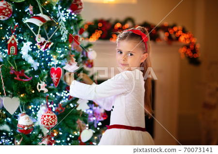 Little girl opening Christmas presents at fire place Little girl opening Christmas presents at fire place 70073141