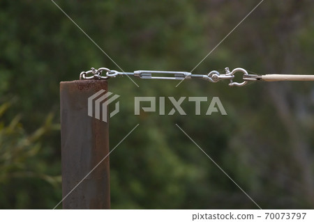 A stainless steel turnbuckle shackle connected to a black metal pole 70073797